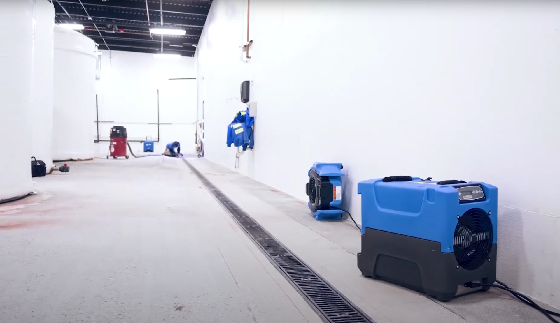 Professional water damage restoration equipment - industrial air movers and dehumidifiers for effective structural drying Water damage restoration equipment including air movers and dehumidifiers set up in a commercial space for professional drying